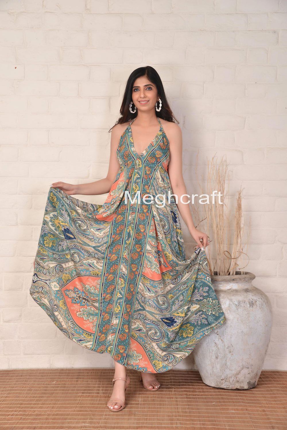 Woman wearing a floral dress with 'Meghcraft' branding against a white brick wall.